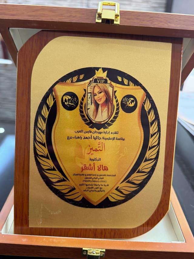 Dr. Hala Ashkar holding medical excellence shield award